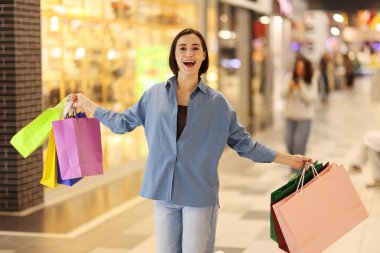 Alışveriş merkezinde farklı çantaları olan bir kadın.