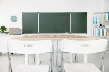 Sınıfta yeşil karatahta, masalar ve sandalyeler var. Tasarım için model