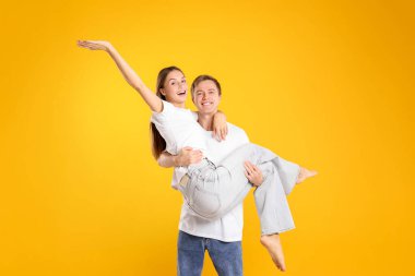 Sarı arka planda güzel kız arkadaşını taşıyan mutlu bir adam. Romantik randevu