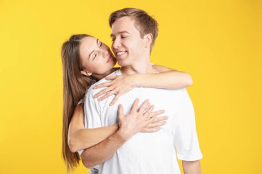 Sarı arka planda kucaklaşan sevimli bir çift. Romantik randevu