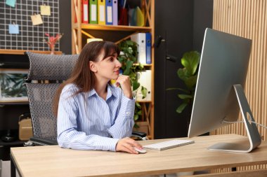 Ofisteki bilgisayarda çalışan genç bir kadın.