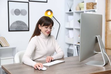 Ofisteki bilgisayarda çalışan genç bir kadın.