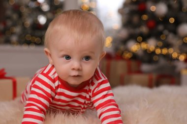 Evde yerde parlak Noel pijamaları içinde sevimli bir bebek.