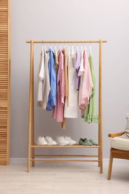 Askıda asılı farklı şık kıyafetler ve açık duvarın yanında ayakkabı.