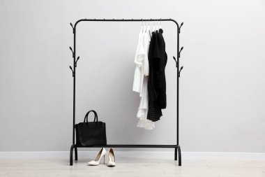 İçerideki duvarın yanında asılı farklı şık kıyafetler, çanta ve ayakkabılar.