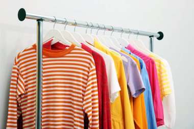 İçerideki ışık duvarının yanındaki raflarda farklı şık kıyafetler ve aksesuarlar var.