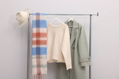 İçerideki duvarın yanındaki raflarda farklı şık kıyafetler ve aksesuarlar var.