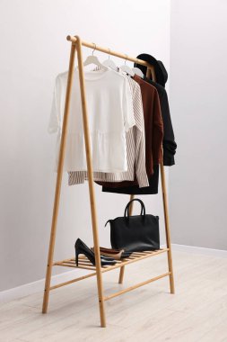 İçerideki duvarın yanında asılı farklı şık kıyafetler, çanta ve ayakkabılar.