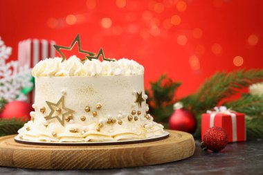 Siyah masanın üzerinde Noel dekoru olan lezzetli pasta kırmızı arka planda bulanık ışıklar, yakın plan