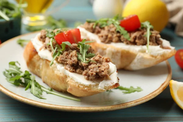 Açık mavi ahşap masada ton balıklı, krem peynirli ve domatesli nefis bruschettalar.