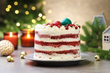 Noel dekorlu lezzetli sünger kek ve gri desenli masa üzümlü üzümlü, bulanık ışıklara karşı, yakın plan. Bokeh etkisi