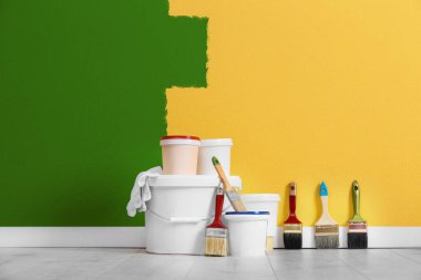 Dekoratör aletleri ve odanın zeminine boya. Duvar kısmen sarı renge boyanmış. İç yenileme