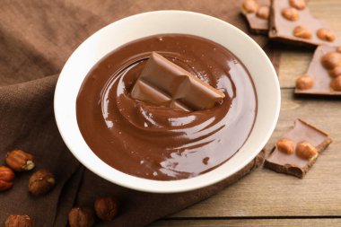 Erimiş çikolata ve fındıklı ahşap masa, yakın plan.