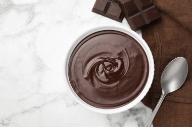 Erimiş çikolata kasede, parçalar ve kaşık beyaz mermer masada, düz yerde. Metin için boşluk
