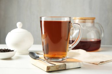 Cam fincanda lezzetli çay ve beyaz masada çay kaşığı gri arka planda, yakın plan