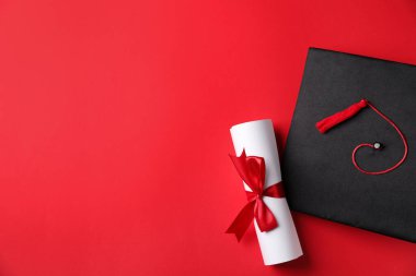 Kırmızı arka planda diploma ve mezuniyet şapkası, düz yatış. Metin için boşluk