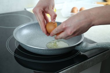 Mutfakta yumurta kıran bir kadın, yakın plan.