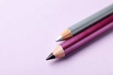 Pembe arka planda renkli göz kalemleri, yakın plan. Metin için boşluk