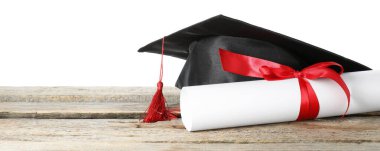 Diploma ve mezuniyet şapkası beyaz arka plana karşı ahşap masada.