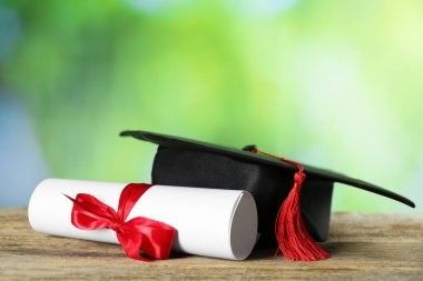 Diploma ve mezuniyet şapkası ahşap masanın üzerinde bulanık arka plan, yakın plan