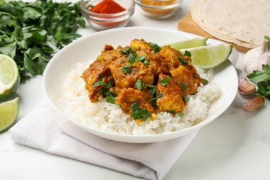 Beyaz mermer masada servis edilen pirinçli tavuk tikka masala, yakın plan.