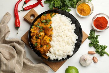 Beyaz mermer masada servis edilen pirinçli tavuk tikka masala.