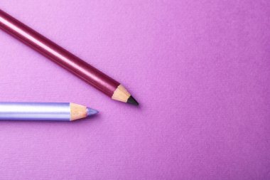 Mor arka planda göz kalemleri, düz yatış. Metin için boşluk