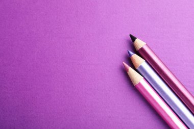 Mor arka planda göz kalemleri, düz yatış. Metin için boşluk