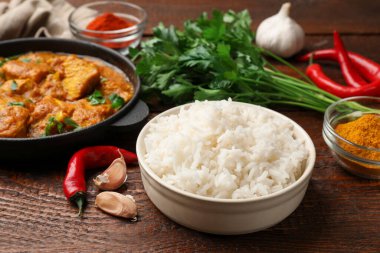 Pişmiş pirinç, tavuk tikka masala ve ahşap masada baharatlar, yakın plan.