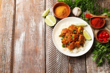 Lezzetli tavuk tikka masala, pirinç, maydanoz, kireç ve baharatlar ahşap masa, düz yatak. Metin için boşluk
