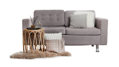 Beyaz yastıklı şık bir kanepe, kahve masası ve halı.