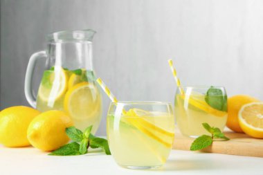 Taze limonata, sürahi, limon ve nane şekeri beyaz masada, yakın plan.