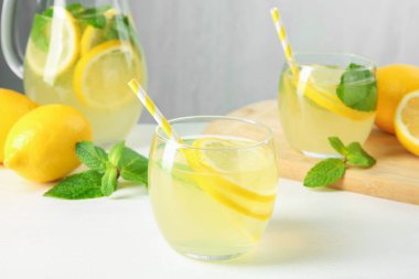 Taze limonata, sürahi, limon ve nane şekeri beyaz masada, yakın plan.