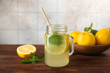 Mason kavanozunda taze limonata, ahşap masada limon ve nane.