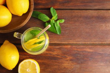 Mason kavanozunda taze limonata, ahşap masada limon ve nane. Metin için boşluk