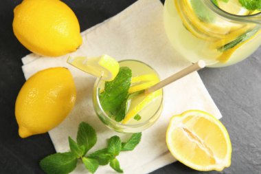 Bardakta taze limonata, sürahi, limon ve nane şekeri siyah masada, düz yatıyordu.
