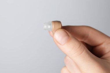 Açık gri arka planda işitme cihazı olan bir kadın, yakın plan. Metin için boşluk