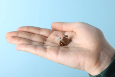 Açık mavi arka planda işitme cihazı olan kadın, yakın plan