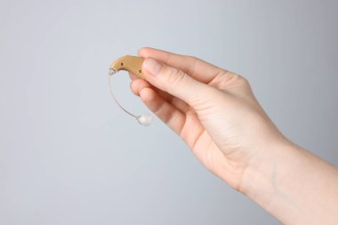 Açık gri arka planda işitme cihazı olan bir kadın, yakın plan. Metin için boşluk