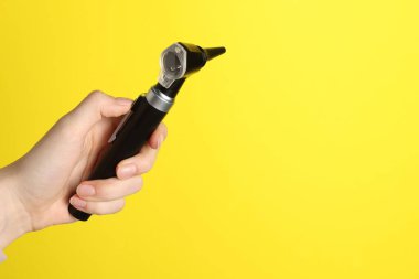 Duyma testi. Sarı arka planda otoskoplu kadın, yakın plan. Metin için boşluk