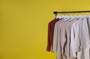 Farklı kadın kıyafetleri sarı arka planda asılı duruyor. Metin için boşluk