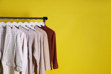 Farklı kadın kıyafetleri sarı arka planda asılı duruyor. Metin için boşluk