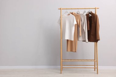 İçerideki duvarın yanındaki askıda asılı farklı şık kıyafetler, metin için yer.