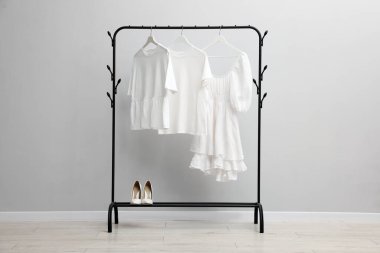 Askıda asılı farklı şık kıyafetler ve açık duvarın yanında ayakkabı.