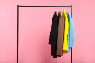 Pembe arkaplanda asılı farklı kıyafetler, metin için boşluk