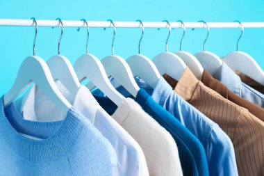 Açık mavi arkaplanda asılı farklı giysiler, yakın plan