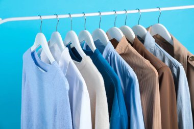 Açık mavi arkaplanda asılı farklı giysiler, yakın plan