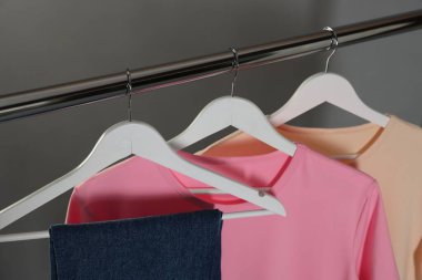 Gri arkaplanda asılı duran farklı şık kıyafetler, yakın plan.