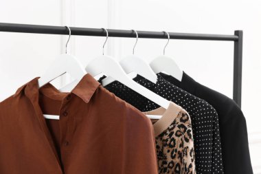 Beyaz duvarın yanında asılı duran farklı kadın kıyafetleri, yakın plan.