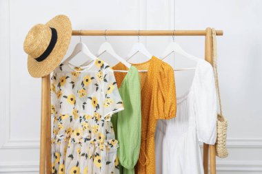 Beyaz duvarın yanında asılı duran farklı kadın kıyafetleri.